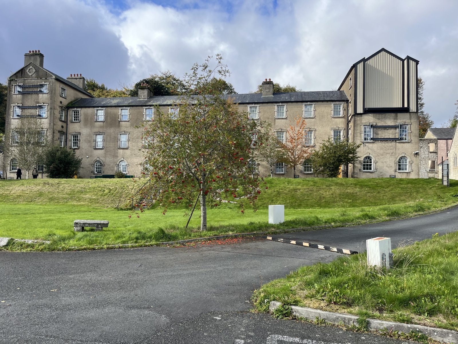 The Glencree Centre's long three-storey stone building, with a rowan tree in berry on the lawn in front